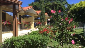A building with a covered porch, outdoor seating, and potted plants. - Aparthotel Boquete (Boquete)