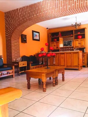 A cozy living room with a brick archway, wooden furniture, and a tiled floor. - Hotel Camino de Villaseca (Guanajuato)