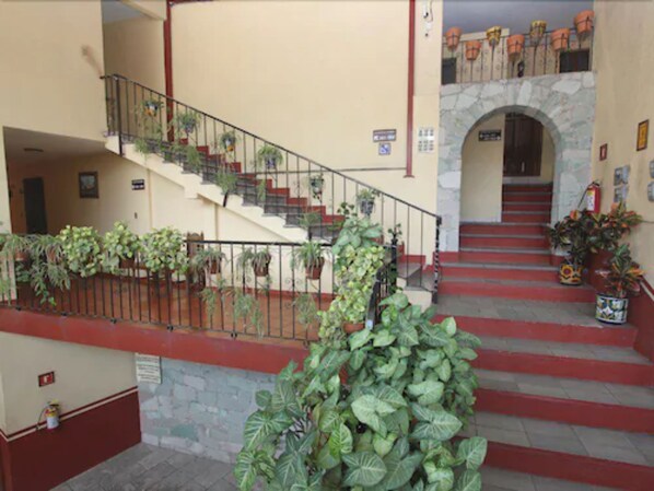 A staircase with red steps, a metal railing, and potted plants. - Hotel Camino de Villaseca (Guanajuato)