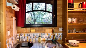 Una cucina compatta con finestra, pensili in legno, lavello e macchina da caffè.