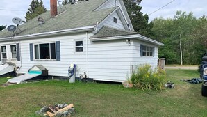 A house with a sloped roof, satellite dishes, and a small shed in the backyard.