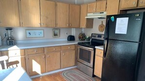 A kitchen with wooden cabinets, a black refrigerator, a stove, and a microwave.