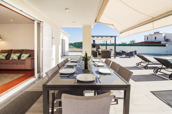 A dining area with a table set for six, outdoor seating, a pool, and a view of the landscape.