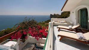 Ein Balkon mit Pool, Liegestühlen und Meerblick.