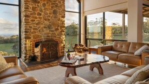 A stone fireplace, leather sofa, and large windows with a view.