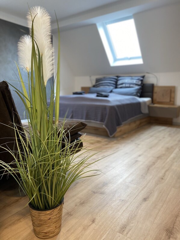 A bedroom with a bed, a window, and a potted plant.