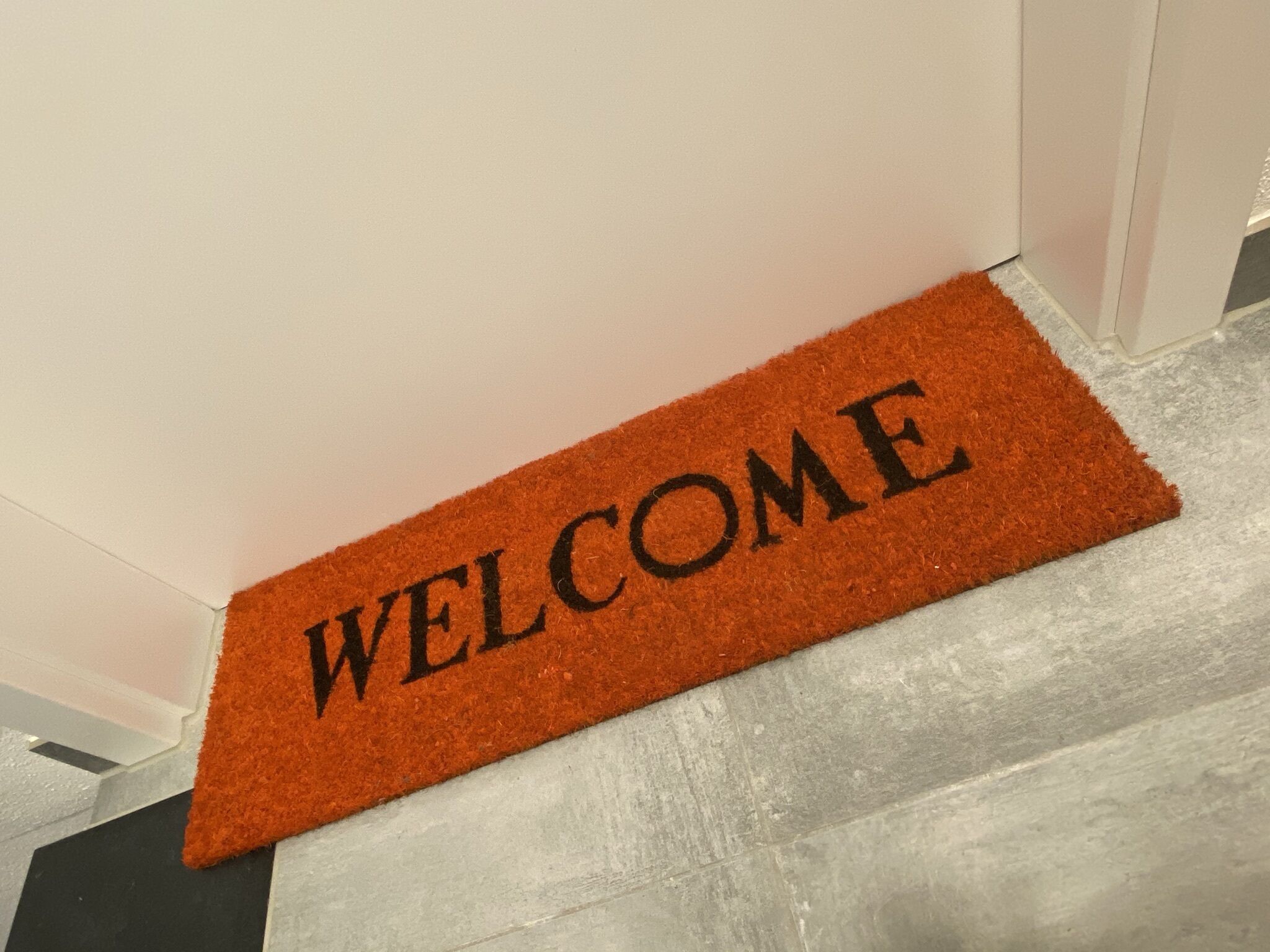 A welcome mat with the word "WELCOME" on a hallway floor.