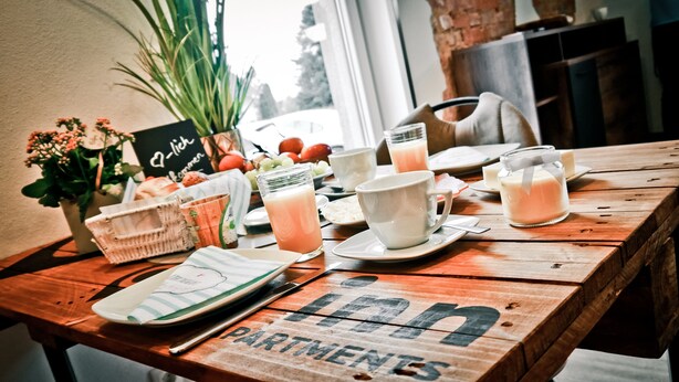 A wooden table with breakfast items, including fruit, milkshakes, and a sign reading "Ich liebe dich". - my inn (Chemnitz)