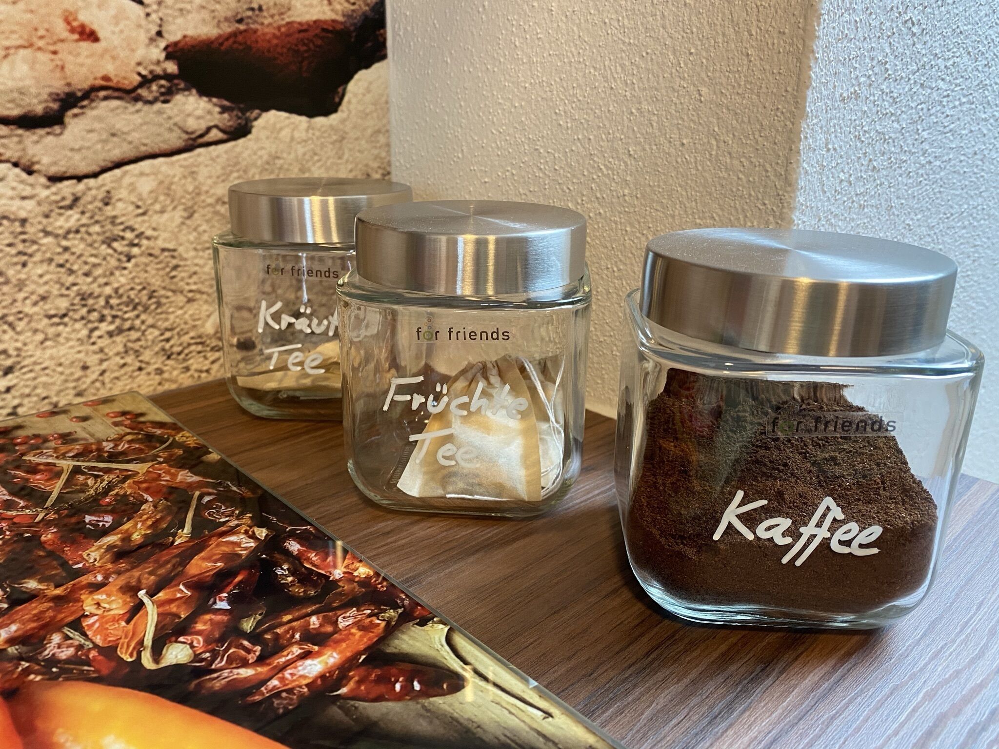 Three glass jars with metal lids, each labeled with a different item: 'Kraut Tee', 'Früch Tea', and 'Kaffee'.