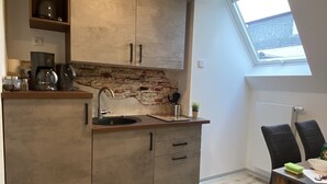 A compact kitchen with a built-in stove, a sink, and a window above the countertop. - my inn (Chemnitz)