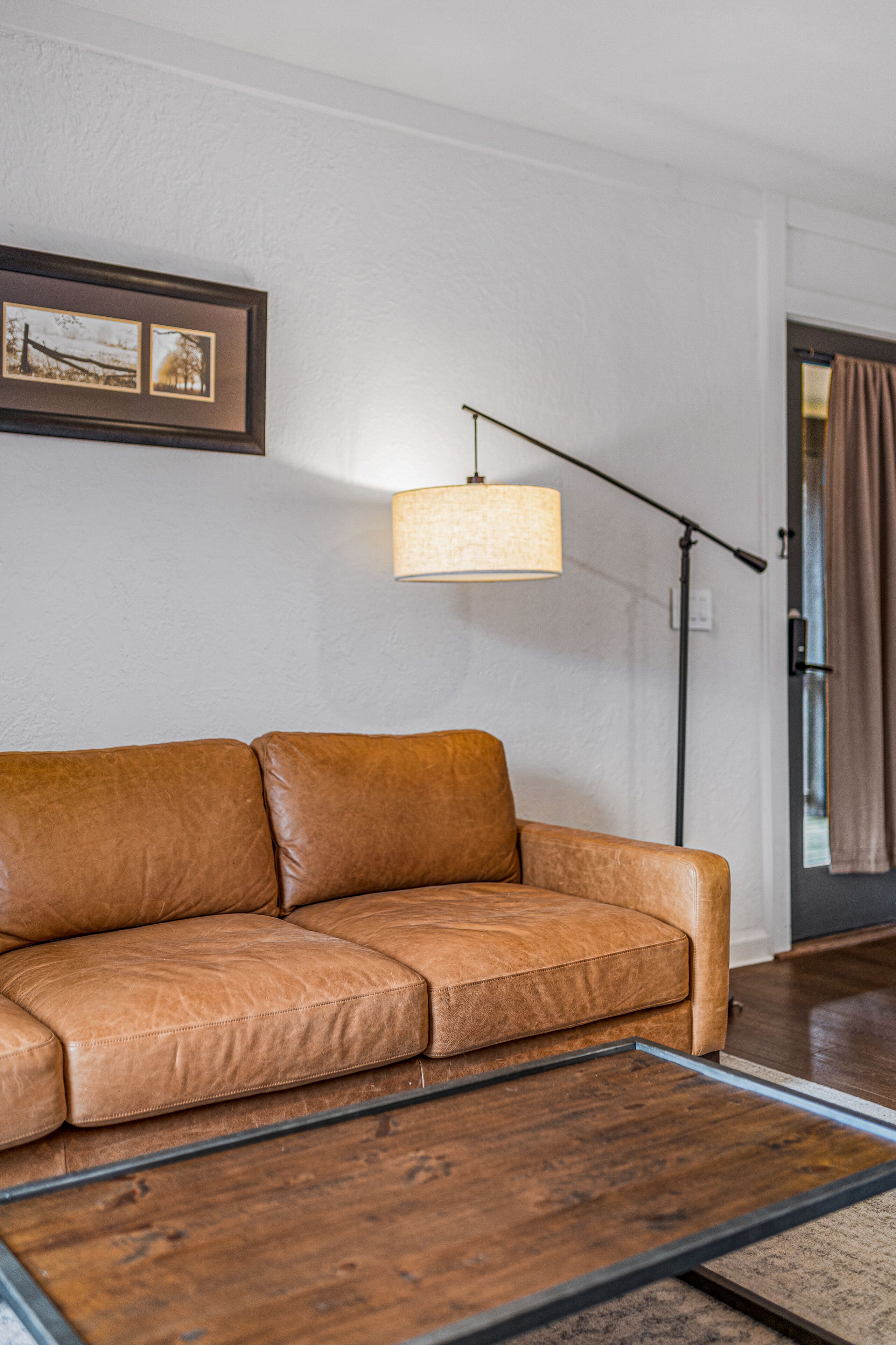 A brown leather sofa, a floor lamp, and a framed picture on the wall.
