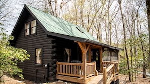 A log cabin with a porch, surrounded by trees. - The Wells Hotel Cashiers (Cashiers)