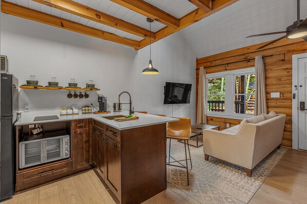 A compact kitchen with wooden beams, a built-in microwave, and a bar area.