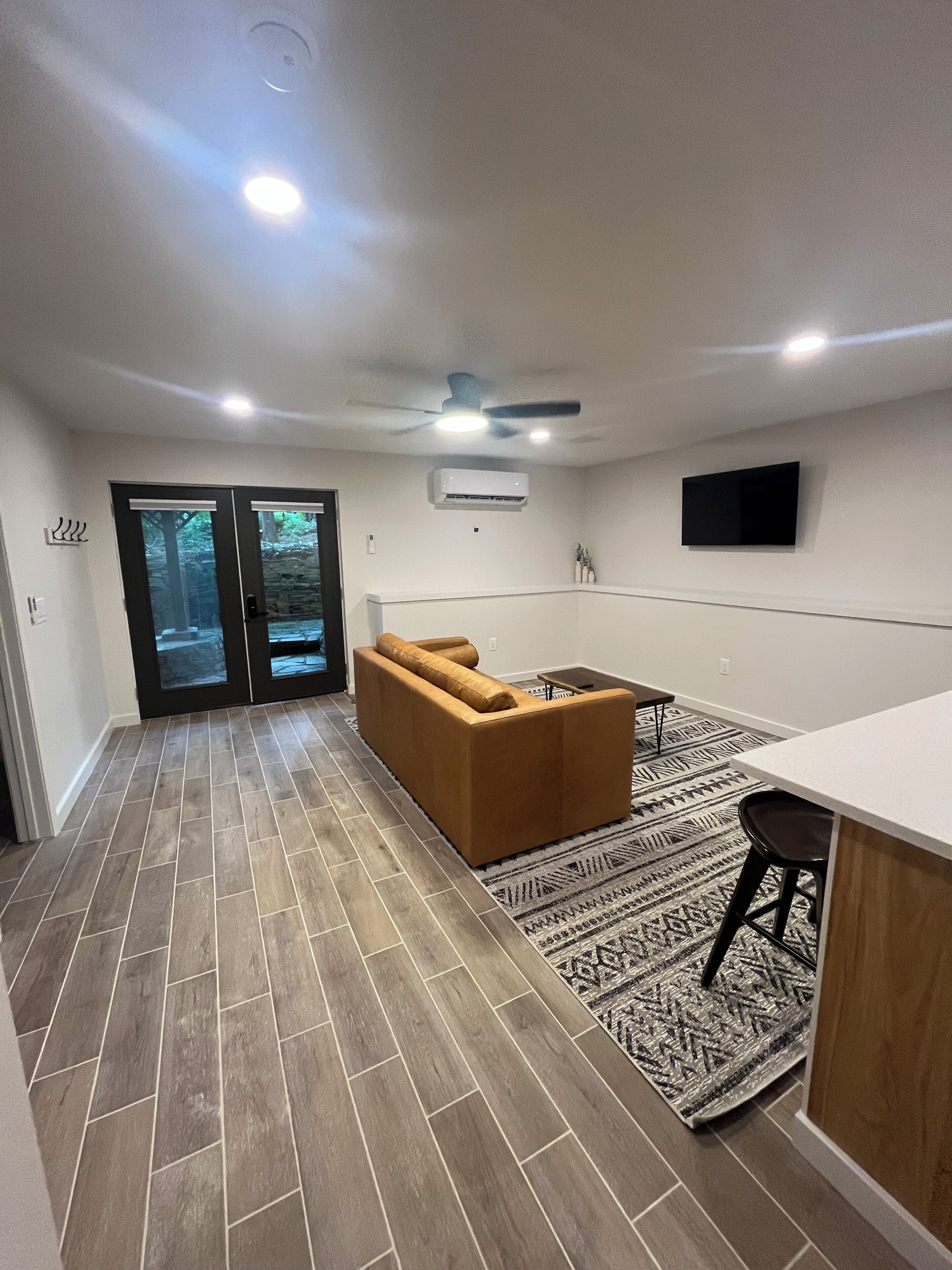 A modern kitchen with a built-in oven, a large window, and a dining area with a bar stool.