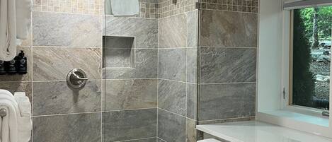 Un baño moderno con ducha, inodoro y ventana con vistas al verdor.
