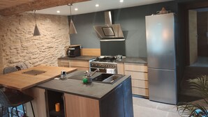 A modern kitchen with a central island, stainless steel appliances, and a stone accent wall.