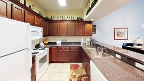 A kitchen with wooden cabinets, a white stove, a sink, and a countertop with a coffee maker.