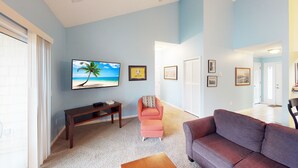 A living room with a television, a sofa, a chair, and a small table.