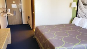 A hotel room with a bed, a desk, and a wardrobe. - The Non-Smoking King Room (Vernal)