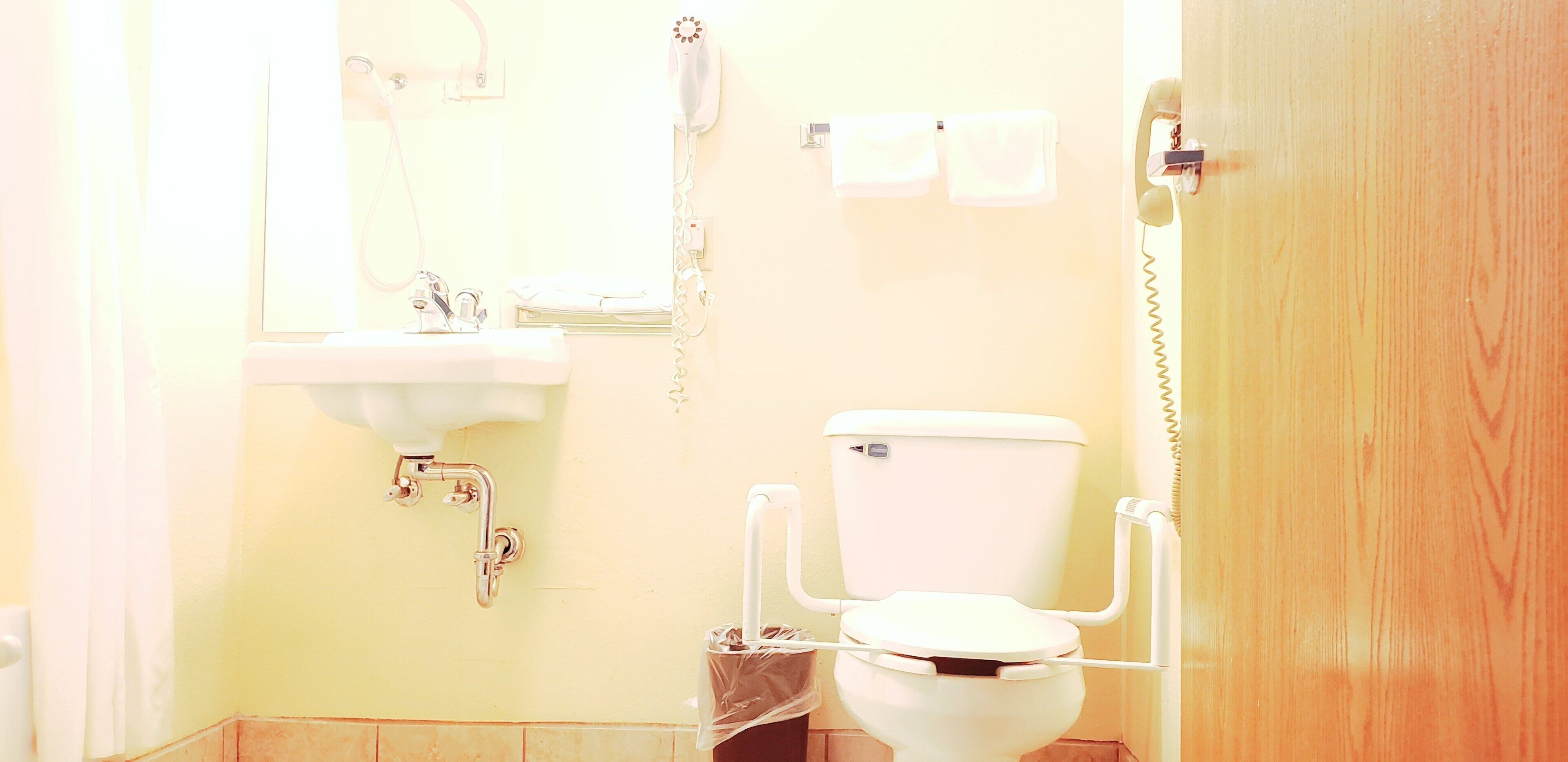 A bathroom with a toilet, sink, and mirror.