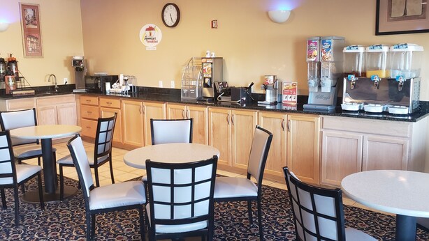 A breakfast area with tables and chairs, a coffee machine, and a juice dispenser. - The Non-Smoking King Room (Vernal)