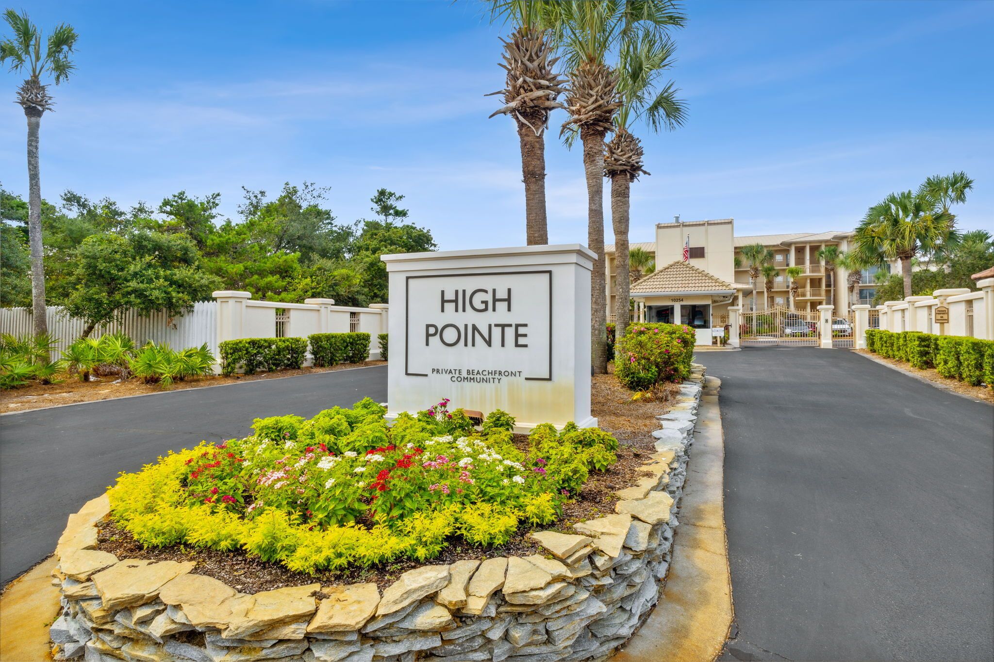 A sign for High Pointe Private Beachfront Community with a landscaped garden and palm trees.