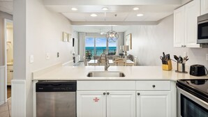 Una cocina moderna con armarios blancos, lavavajillas, estufa y vistas al exterior.
