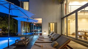 Ein moderner Außenbereich mit Liegestühlen, einem Pool und Sonnenschirmen.