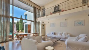 Ein geräumiges Wohnzimmer mit großem Fenster, Essbereich und Balkon mit Geländer.