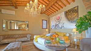 Une chambre spacieuse avec un grand lit, un coin salon avec un canapé, une table ronde avec des boissons et un lustre.
