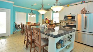 A kitchen with a central island, white cabinets, stainless steel appliances, and a teal color scheme. - Sum Beach- Great Beach Views-4 bedroom 3 bath home sleeps 13. (Crystal Beach)