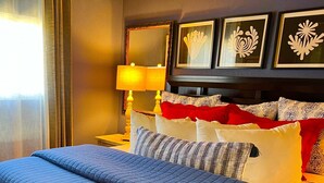 A hotel room with a bed, a nightstand, a lamp, and framed artwork on the wall. - Oceanfront Two bedroom Condominium  (Homer)