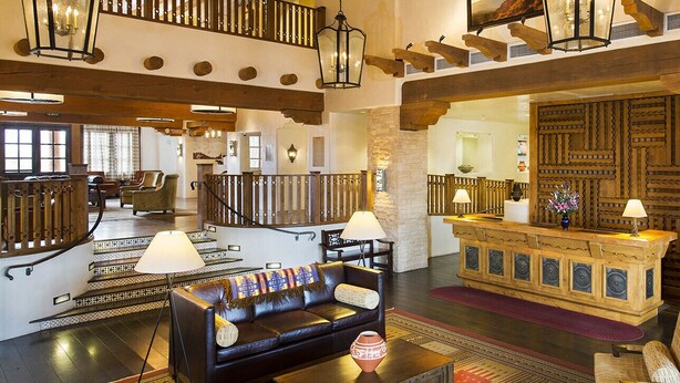 A spacious lobby with a leather sofa, a reception desk, and a staircase.