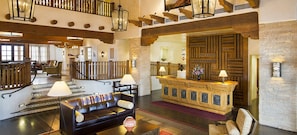 Eine geräumige Lobby mit einer Ledersofa, einem Empfangstresen und einer Treppe.
