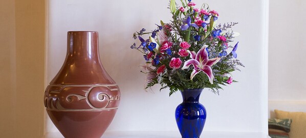 Dos jarrones, uno marrón y otro azul, con arreglos florales.