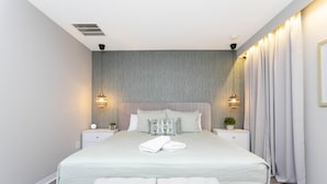 Een moderne slaapkamer met een groot bed, twee nachtkastjes en een bankje.