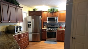 A kitchen with wooden cabinets, stainless steel appliances, a microwave, and a stove. - Beautiful Villa in the Heart of Florida's Friendliest Active Adult Community (The Villages)