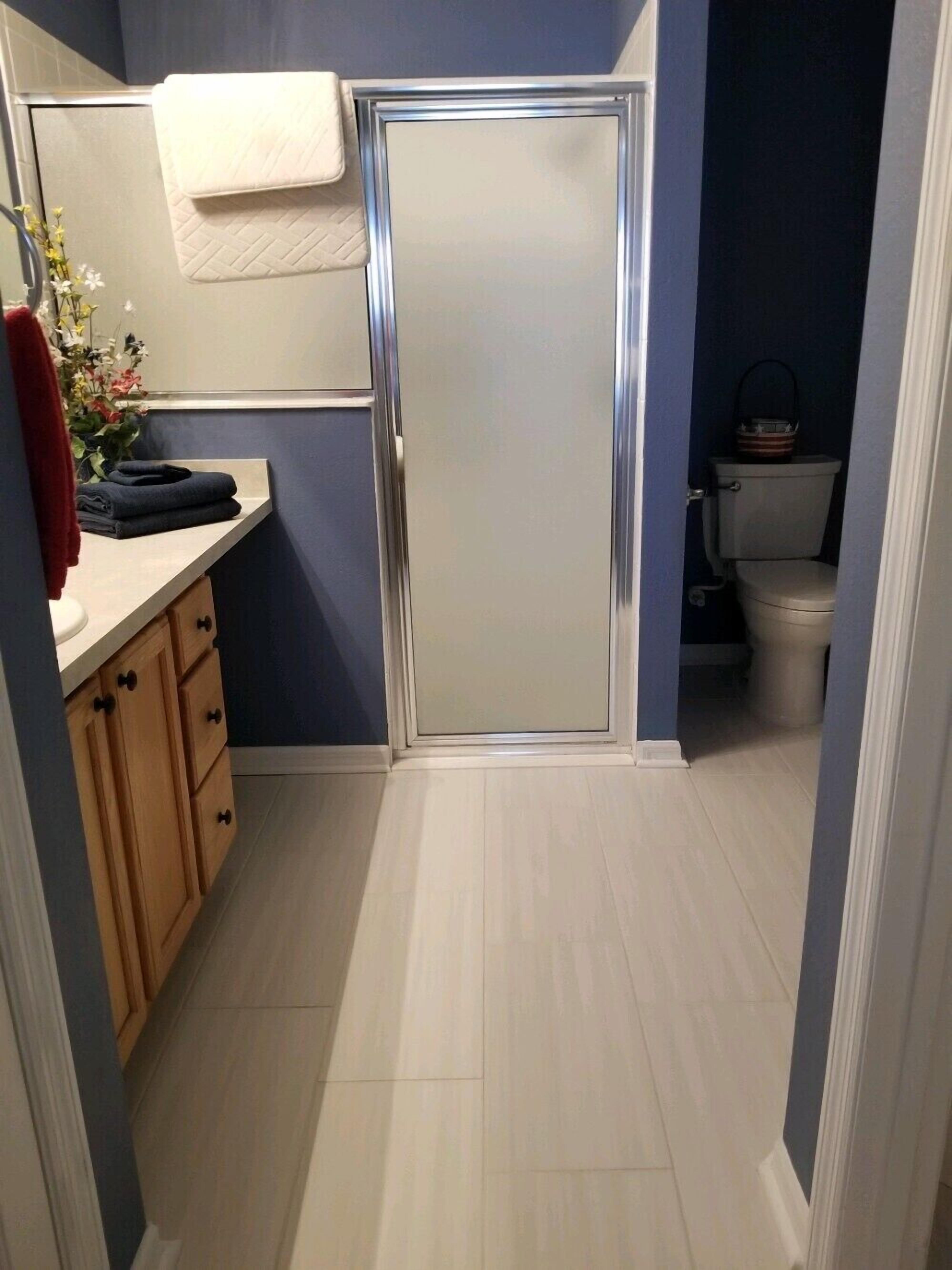 Une salle de bain avec une douche, des toilettes et un lavabo, ainsi qu’une serviette et des vêtements pliés.