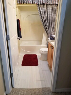 A bathroom with a bathtub, toilet, and a red rug. - Beautiful Villa in the Heart of Florida's Friendliest Active Adult Community (The Villages)