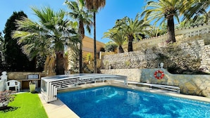 A swimming pool with a stone wall and palm trees. - Villa Camelia - Benitachell, Costa Blanca (Benitachell)