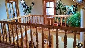 A wooden staircase with a railing, a ceiling with a geometric pattern, and several potted plants. - Casa Lacry (Manastirea Humorului)