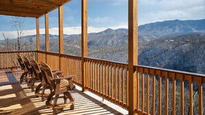 Eine Holzterrasse mit Stühlen und Tisch, mit Blick auf eine Berglandschaft.