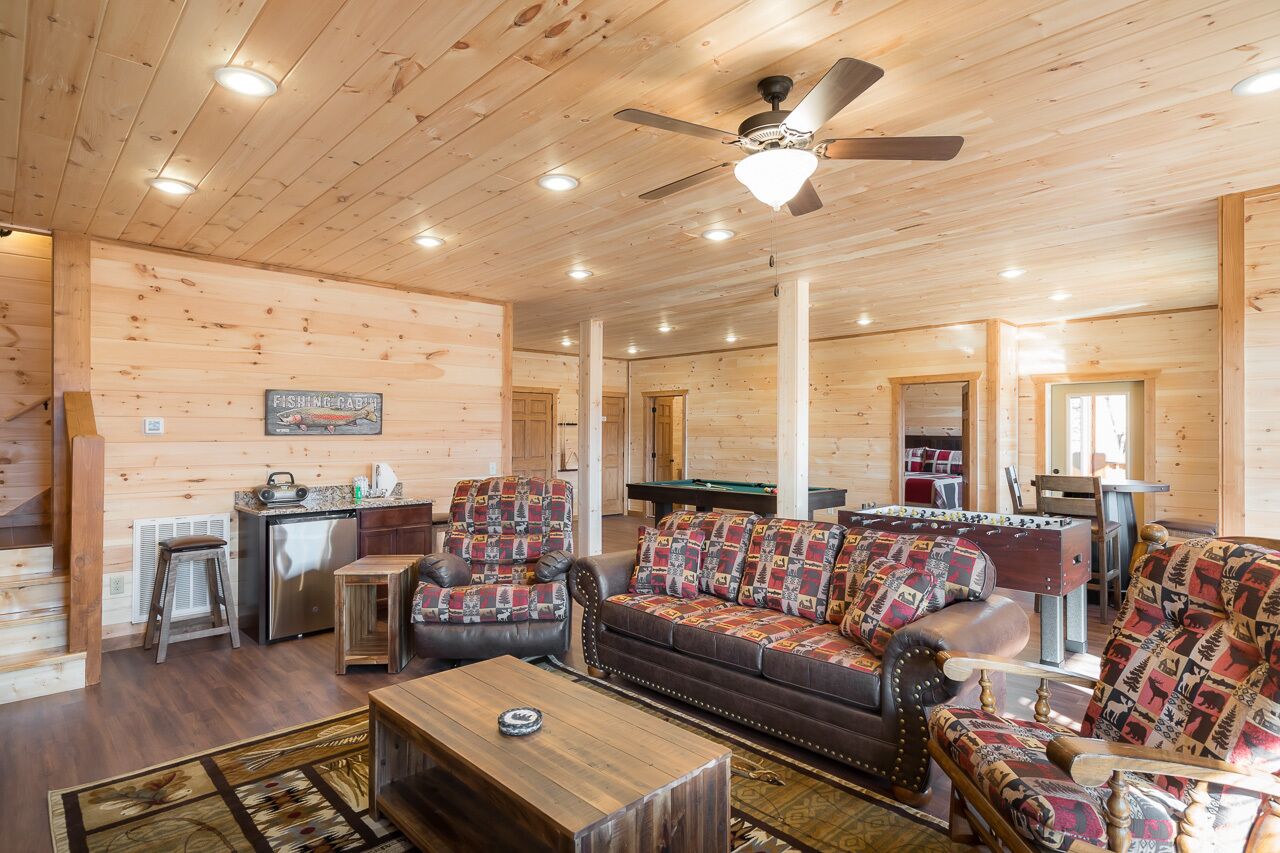 A spacious wooden cabin interior with a living room, kitchen, and a pool table.