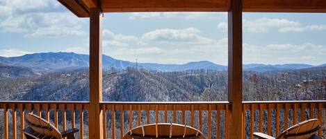 Eine Holzterrasse mit Adirondack-Stühlen mit Blick auf eine gebirgige Landschaft.