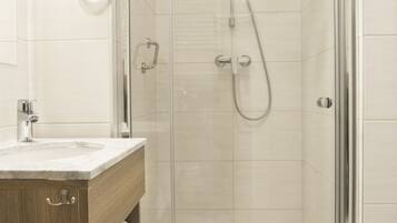 Ein modernes Badezimmer mit einer Glaskabine zur Dusche, einem Holzwaschtisch mit Waschbecken und einem Handtuchhalter.