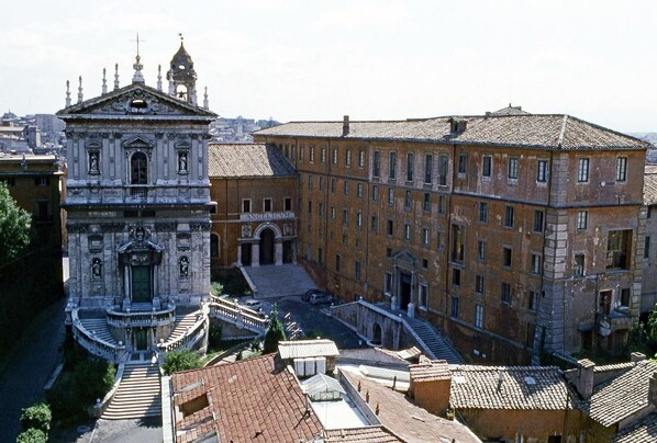 A historic building with a central courtyard, a bell tower, and a staircase leading to the entrance. - Monti Urbana Terrace (Roma)