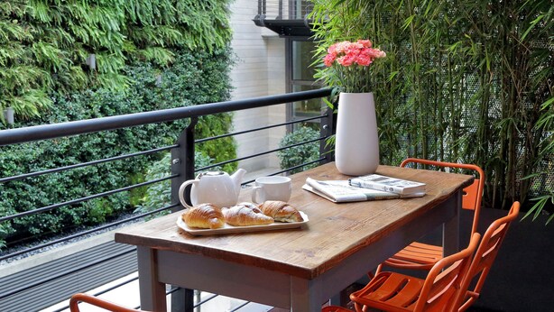 Une table en bois, un vase blanc, une assiette de croissants et une théière.