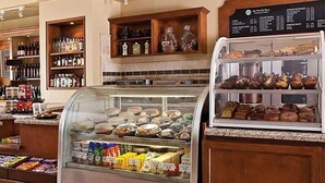 Vitrine de uma padaria com diversos produtos de panificação e um balcão de charcutaria com produtos embalados.