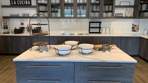 A modern kitchen with dark wood cabinets, a marble countertop, and a sign reading "LA CUCINA". - Residence Inn by Marriott Nashville Mt. Juliet (Mount Juliet)