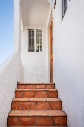 A set of terracotta-tiled stairs leading to a white door with a window above it.